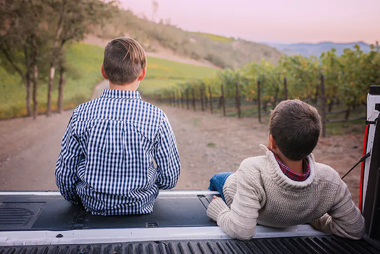 Two boys sitting on the back of a pickup truck